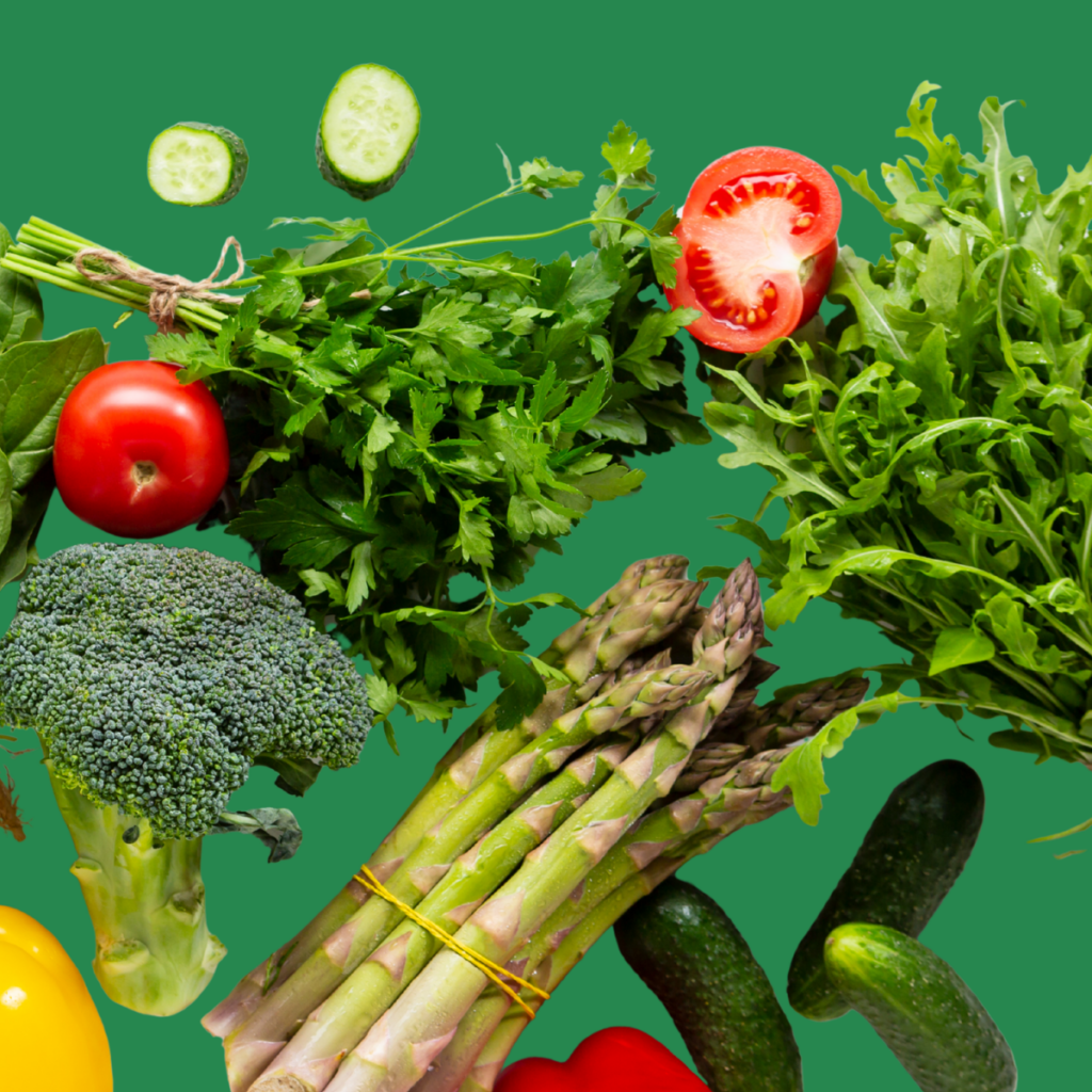 Fresh vegetables including cucumber, tomato, parsley, broccoli, asparagus and rocket scattered on a green background.