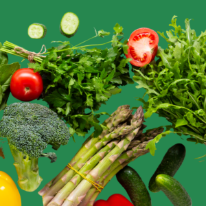 Fresh vegetables including cucumber, tomato, parsley, broccoli, asparagus and rocket scattered on a green background.